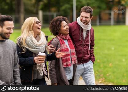 people, friendship, communication and international concept - group of happy friends with coffee walking along autumn park and laughing