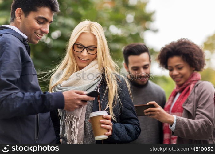 people, friendship, communication, technology and international concept - group of happy friends with smartphone and coffee outdoors