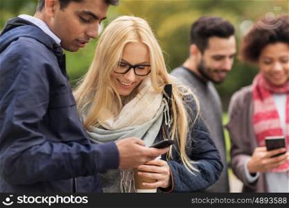 people, friendship, communication, technology and international concept - group of happy friends with smartphone and coffee outdoors