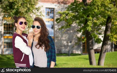 people, friendship, fashion, education and teens concept - happy smiling pretty teenage girls in sunglasses over summer campus background