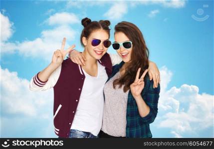 people, friendship, fashion, summer and teens concept - happy smiling pretty teenage girls in sunglasses showing peace hand sign over blue sky and clouds background