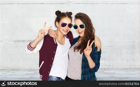 people, friendship, fashion, summer and teens concept - happy smiling pretty teenage girls in sunglasses showing peace hand sign over urban street background