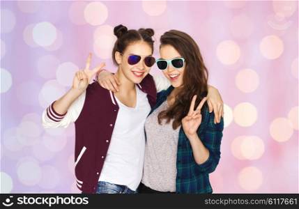 people, friendship, fashion, summer and teens concept - happy smiling pretty teenage girls in sunglasses showing peace hand sign over pink holidays lights background