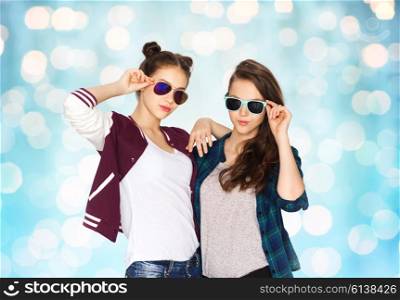 people, friendship, fashion, summer and teens concept - happy smiling pretty teenage girls in sunglasses over blue holidays lights background