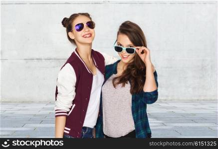 people, friendship, fashion, summer and teens concept - happy smiling pretty teenage girls in sunglasses over gray urban street background