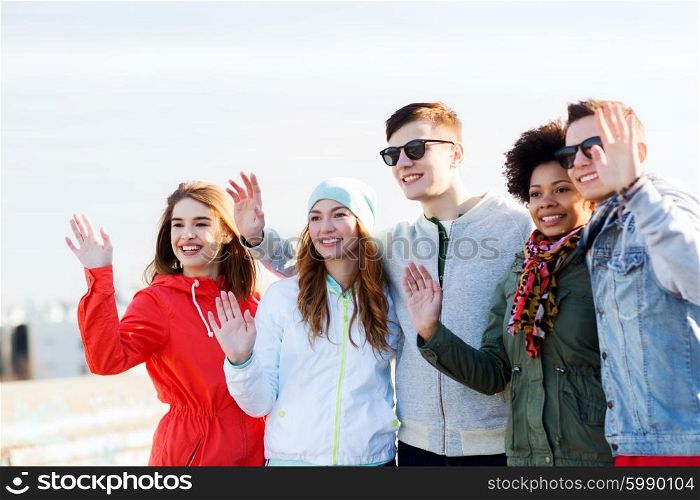 people, friendship, gesture and international concept - happy teenage friends waving hands on outdoors