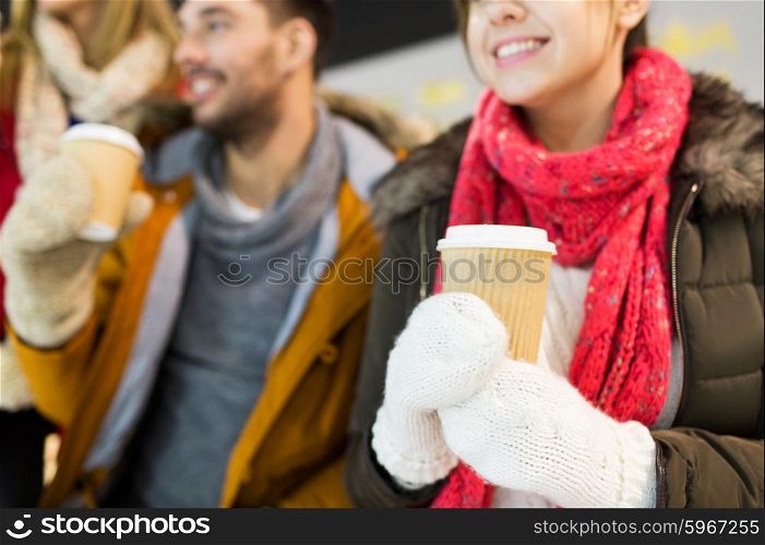 people, friendship, hot drinks and leisure concept - close up of happy friends drinking from paper coffee cups on skating rink