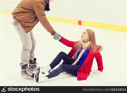 people, friendship, sport and leisure concept - smiling man helping women to rise up on skating rink