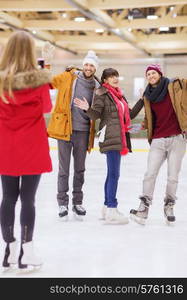 people, friendship, technology and leisure concept - happy friends taking photo with smartphone on skating rink