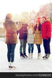 people, friendship, technology and leisure concept - happy friends taking picture with smartphone on ice skating rink outdoors. happy friends with smartphone on ice skating rink