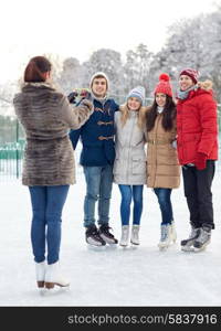 people, friendship, technology and leisure concept - happy friends taking picture with smartphone on ice skating rink outdoors