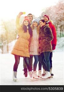 people, friendship, technology and leisure concept - happy friends taking selfie with smartphone on ice skating rink outdoors. happy friends with smartphone on ice skating rink