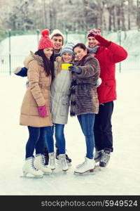 people, friendship, technology and leisure concept - happy friends taking selfie with smartphone on ice skating rink outdoors