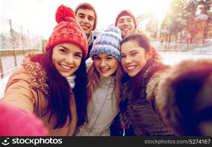 people, friendship, technology, winter and leisure concept - happy friends taking selfie with smartphone or camera outdoors. happy friends taking selfie with smartphone