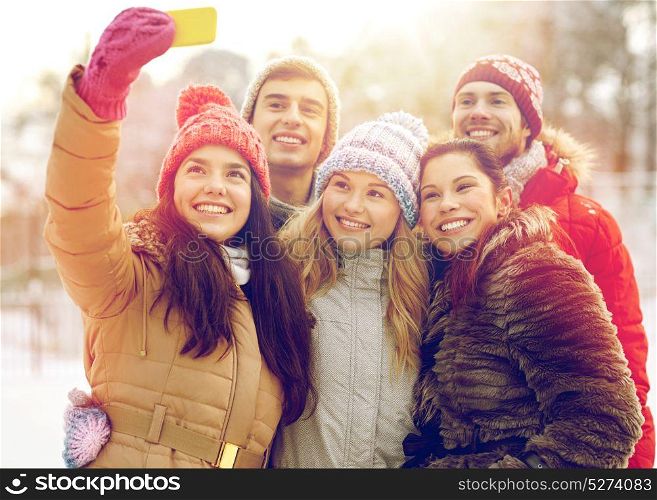 people, friendship, technology, winter and leisure concept - happy friends taking selfie with smartphone outdoors. happy friends taking selfie with smartphone