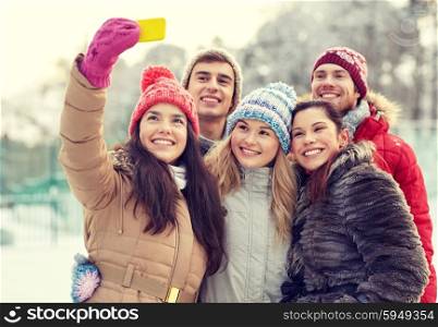 people, friendship, technology, winter and leisure concept - happy friends taking selfie with smartphone outdoors