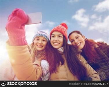 people, friendship, technology, winter and leisure concept - happy teenage girls taking selfie with smartphone outdoors. happy teenage girls taking selfie with smartphone