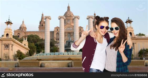 people, friendship, travel, tourism and teens concept - happy smiling pretty teenage girls in sunglasses showing peace hand sign over national museum of barcelona background