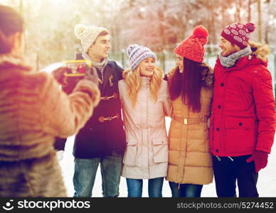 people, friendship, winter, technology and leisure concept - happy friends taking picture with smartphone outdoors. happy friends taking picture with smartphone