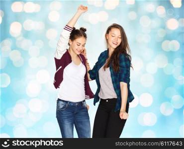 people, fun, teens and friendship concept - happy smiling pretty teenage girls dancing over blue holidays lights background
