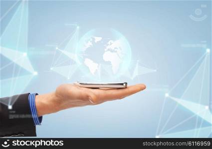 people, future technology, science and business concept - close up of male hand with smartphone and earth globe projection