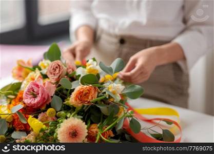 people, gardening and floral design concept - close up of close up of woman or floral artist making bunch of flowers at studio. close up of woman making bunch of flowers on table
