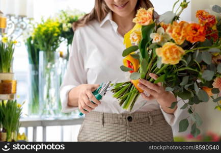 people, gardening and floral design concept - close up of happy smiling woman or floral artist making bunch of flowers and cutting stems with pruning shears over shop background. happy woman making bunch of flowers at shop