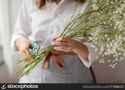 people, gardening and floral design concept - close up of woman or floral artist cutting gypsophila stem with pruning shears at home. woman cutting flower stem with pruning shears