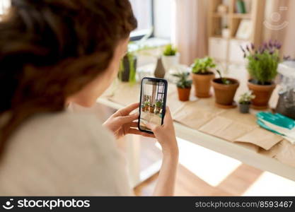 people, gardening and housework concept - close up of woman with smartphone photographing pot flowers at home. woman with smartphone photographing pot flowers