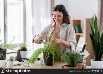 people, gardening and housework concept - happy woman cutting fern flower&rsquo;s leaves with pruner at home. woman cutting flower&rsquo;s leaves with pruner at home