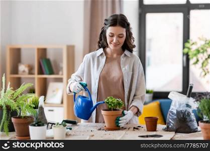 people, gardening and housework concept - happy woman in gloves with watering can planting pot flowers at home. happy woman planting pot flowers at home