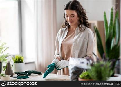 people, gardening and housework concept - happy woman with gloves planting flowers at home. happy woman with gloves planting flowers at home