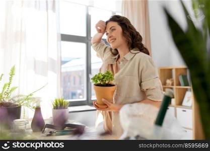 people, gardening and housework concept - tired smiling woman planting pot flowers at home. tired woman planting pot flowers at home