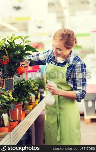 people, gardening and profession concept - happy woman or gardener taking care of mandarin tree in greenhouse