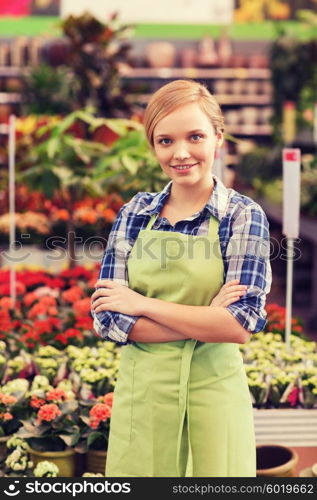 people, gardening and profession concept - happy woman with flowers in greenhouse