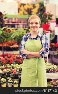 people, gardening and profession concept - happy woman with flowers in greenhouse