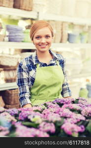 people, gardening and profession concept - happy woman with flowers in greenhouse