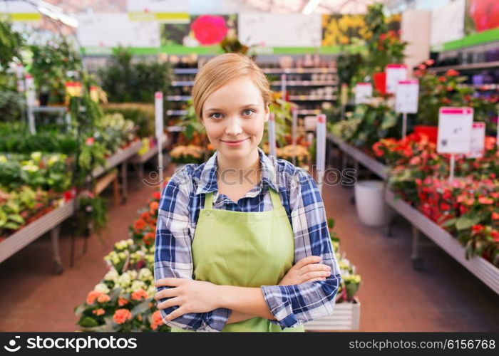 people, gardening and profession concept - happy woman with flowers in greenhouse