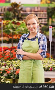 people, gardening and profession concept - happy woman with flowers in greenhouse