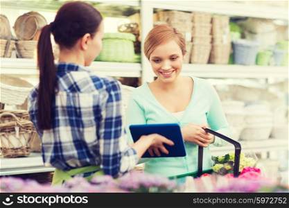 people, gardening, shopping, sale and consumerism concept - happy gardener with tablet pc helping woman with choosing flowers at flower shop
