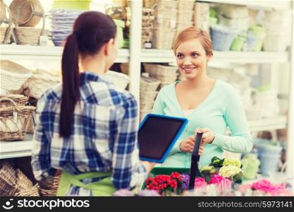 people, gardening, shopping, sale and consumerism concept - happy gardener with tablet pc helping woman with choosing flowers at flower shop