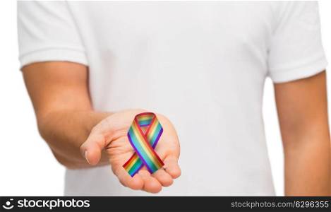 people, gay pride and homosexuality concept - male hand holding rainbow awareness ribbon. male hand holding gay pride awareness ribbon