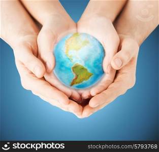 people, geography, population and peace concept - close up of woman and man hands with earth globe showing american continent over blue background