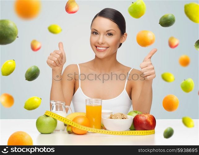 people, gesture and diet concept- happy asian woman with healthy food showing thumbs up over gray background with falling fruits