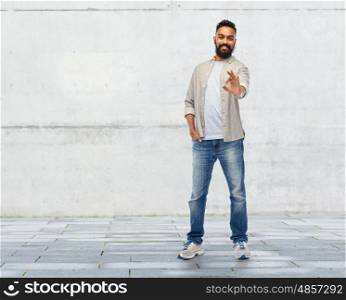 people, gesture and ethnicity concept - happy smiling indian man showing ok hand sign over stone wall background