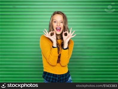 people, gesture and fashion concept - happy young woman or teen girl in casual clothes showing ok hand sign over green ribbed wall background. happy young woman or teen showing ok hand sign