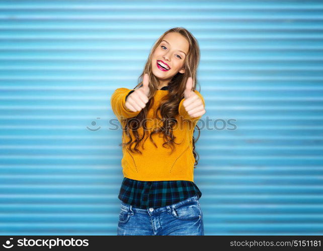 people, gesture and fashion concept - happy young woman or teen girl in casual clothes showing thumbs up over blue ribbed wall background. happy young woman or teen girl showing thumbs up