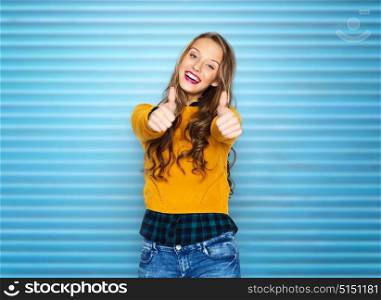 people, gesture and fashion concept - happy young woman or teen girl in casual clothes showing thumbs up over blue ribbed wall background. happy young woman or teen girl showing thumbs up