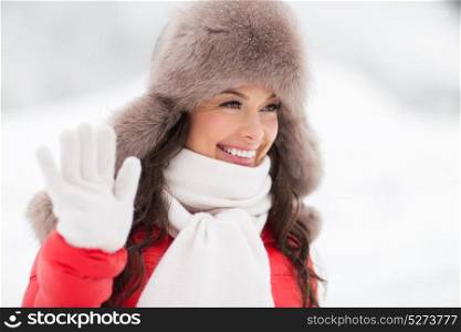 people, gesture and leisure concept - happy smiling woman in winter fur hat waving hand outdoors. happy woman in winter fur hat waving hand outdoors