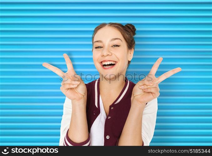 people, gesture and teens concept - happy smiling pretty teenage girl showing peace sign over blue ribbed background. happy smiling teenage girl showing peace sign